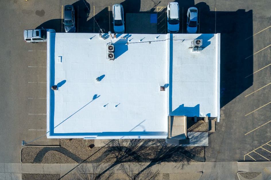 Aerial view of the same commercial building with a new white reflective membrane roof