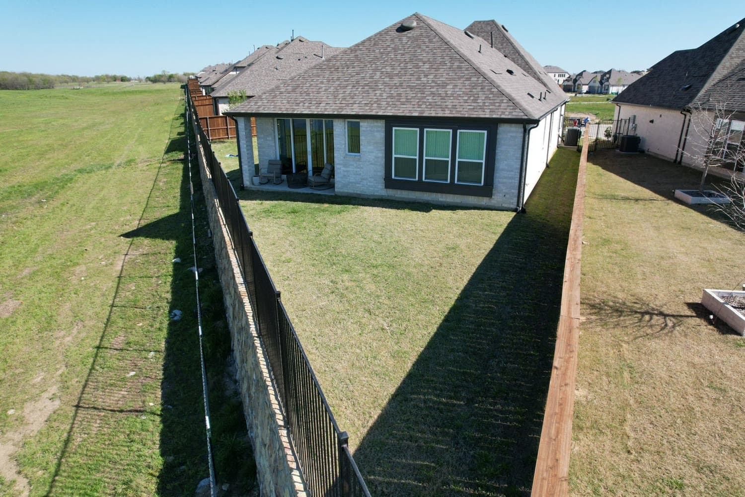 Aerial view of a stone home's bare backyard before the covered patio was built